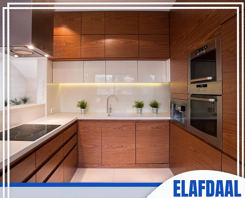 فني تركيب مطابخ بجدة 0594257100 الأفضل مطبخ خشبي أنيق بتصميم حرف U، يتميز بوحدات خشبية بنية وواجهات بيضاء زجاجية.