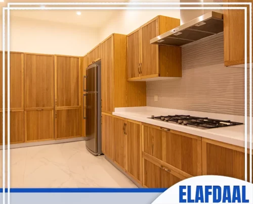 اسقف مطابخ المنيوم بجدة 0594257100 الأفضل تصميم مطبخ حديث بألواح خشبية فاتحة، مزود بأجهزة متكاملة وسطح عمل أبيض نظيف.