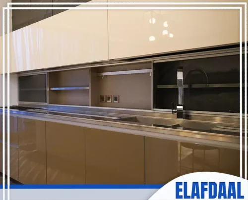 فني تركيب مطابخ جدة 0594257100 الأفضل مطبخ عصري بتصميم لامع باللون البيج اللامع، يضم وحدات سفلية ورفوف عرض علوية.