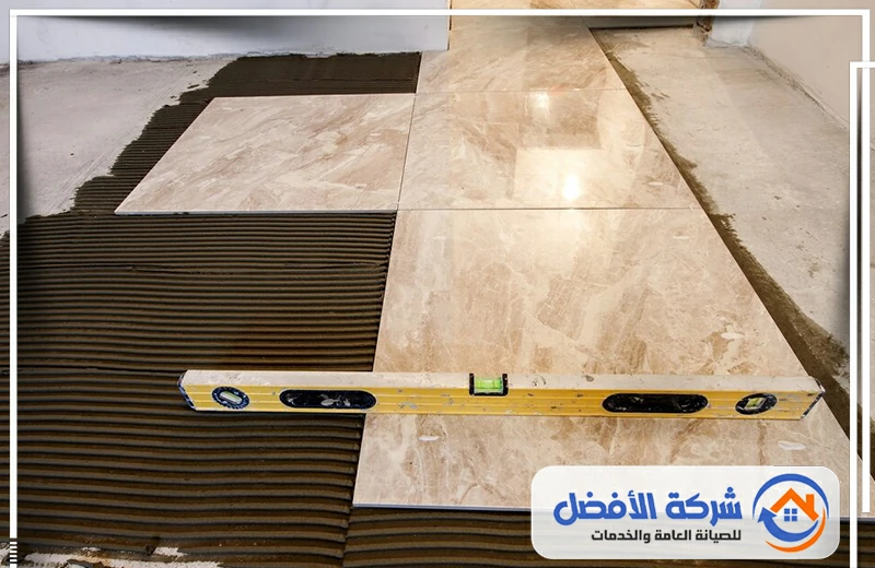 حمام حديث ببلاط رخامي أبيض مع عروق رمادية، يضم مرآة مضاءة وحوض وغربي.