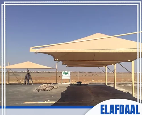 سواتر قماش في الطائف 0558441399 شركة الافضل مظلات سيارات أو تجمعات كبيرة ذات تصميم هرمي واسع، تتميز بالبساطة والوظيفة في موقع خارجي.