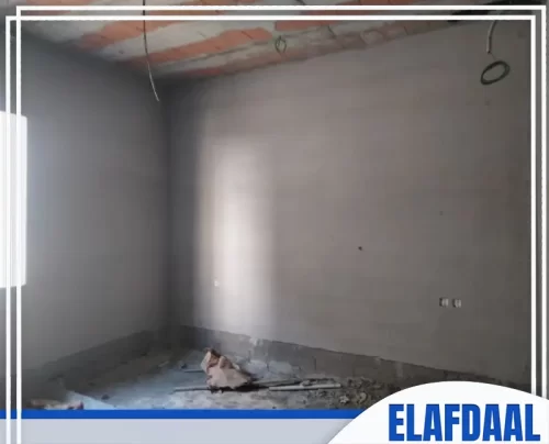 شركة لياسة بالرياض غرفة داخلية غير مكتملة، جدرانها مغطاة بالمحارة الرمادية، مع أسقف من الطوب الأحمر.