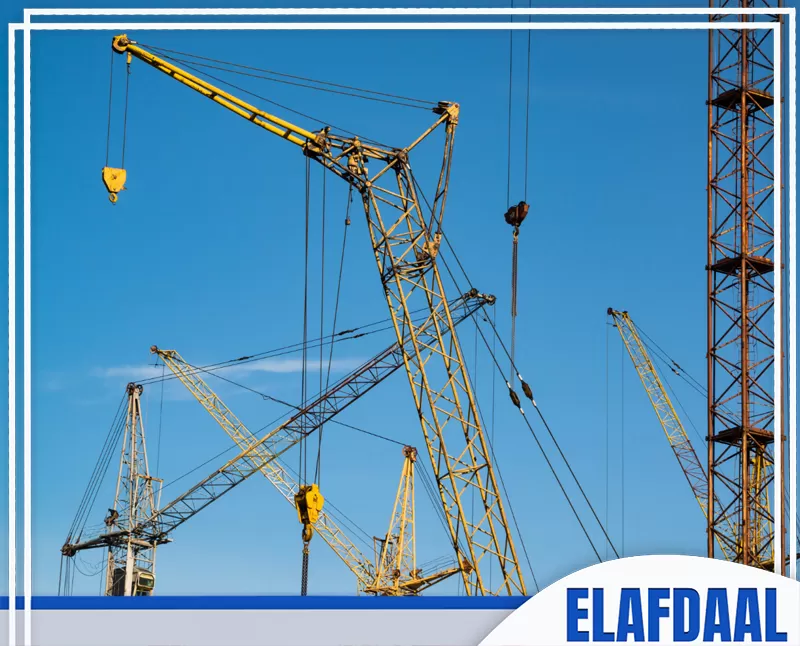 الصورة توضح عدة رافعات برجية في موقع بناء، تستخدم لرفع المعدات والمواد الثقيلة أثناء تنفيذ الأعمال الإنشائية.