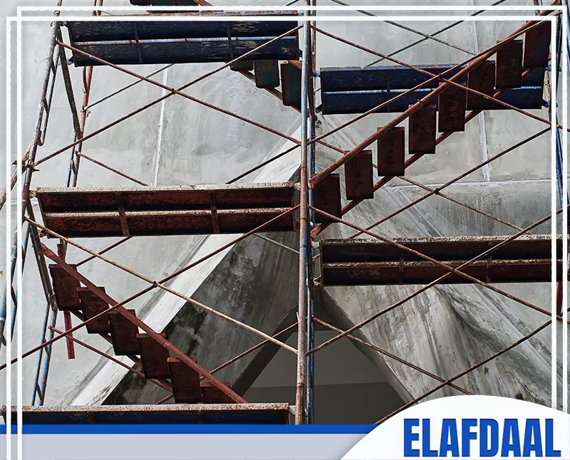 سقالات معدنية مركبة أمام مبنى قيد التشطيب، مع منصات وممرات عمل تُستخدم للوصول إلى الواجهة أثناء أعمال الصيانة أو البناء.