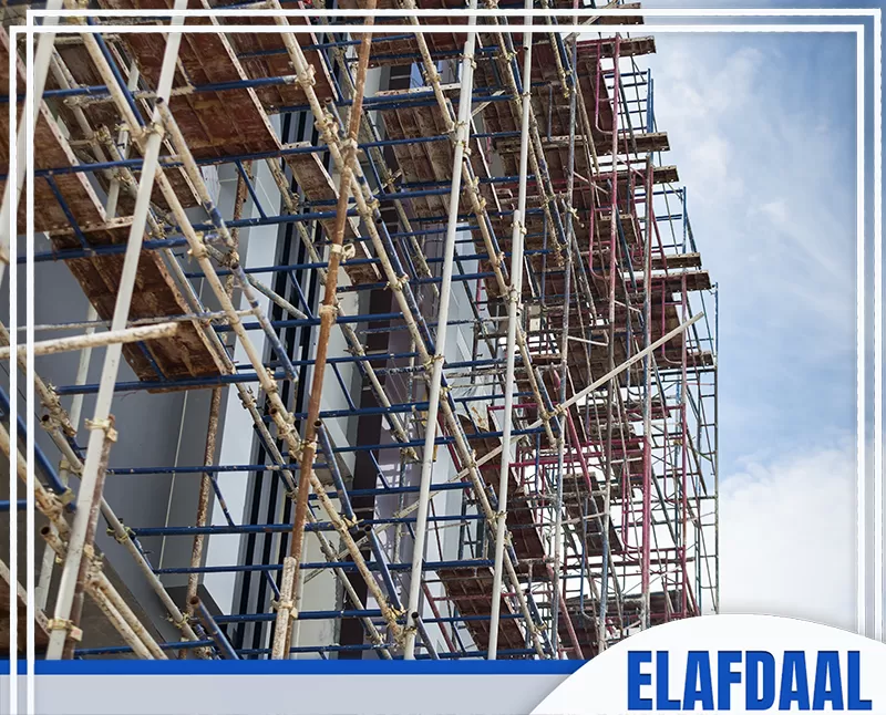 سقالات معدنية ممتدة على واجهة مبنى قيد التشطيب، مع منصات عمل متعددة تُستخدم للوصول إلى الطوابق وتنفيذ أعمال الواجهة.